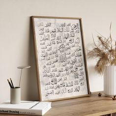 an arabic calligraphy is displayed on a shelf next to a vase with dried grass