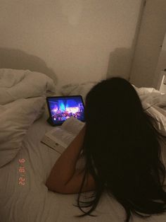 a woman laying on top of a bed next to a tablet