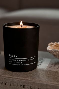 a black candle sitting on top of a book next to a seashell and sea shell