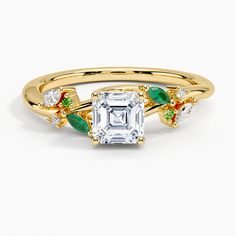 an emerald and diamond engagement ring with leaves on the band, set in yellow gold