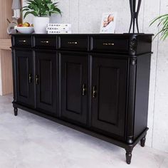 a black buffet with gold handles and doors on it's sides is shown in front of a white wall