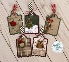 four tags are hanging on a wooden surface with christmas decorations and ribbons around them, all decorated in different colors