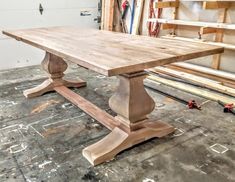 a large wooden table sitting on top of a floor next to some wood planks