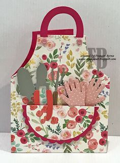 a paper bag with flowers and gardening utensils in it