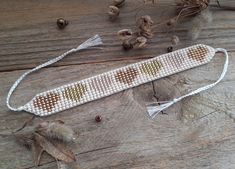 a beaded bracelet with hearts and tassels on a wooden table next to dried flowers