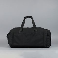 a black duffel bag sitting on top of a white floor next to a gray wall