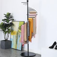 there is a coat rack with clothes hanging on it next to a potted plant