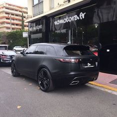 a black range rover parked in front of a store