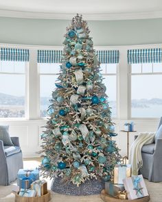 a decorated christmas tree in a living room with blue and silver ornaments on the top