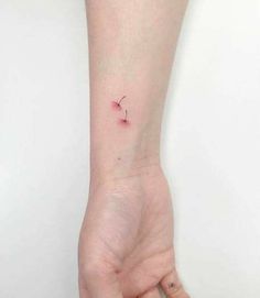 a person's hand with a tiny pink flower tattoo on their left wrist,