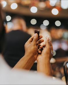 two hands holding a small cup in the middle of a room