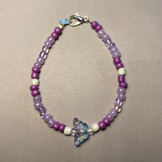 Elevate your ensemble with our Whimsical Butterfly Purple Beaded Bracelet. Handcrafted with care, this charming piece features an assortment of purple beads in various shades, complemented by delicate white pearl-colored beads for an added touch of elegance. At its heart, a delightful butterfly-shaped bead in clear blue and purple tones steals the spotlight, infusing the bracelet with a whimsical allure. Available in two lengths: 18cm and 20cm, this bracelet offers versatility and comfort for everyday wear. Whether worn as a personal statement or gifted to a loved one, our Whimsical Butterfly Purple Beaded Bracelet brings a playful pop of color and style to any outfit. This was also inspired by the K-Pop group BTS and their beautiful song Butterfly Whimsical Butterfly, Butterfly Purple, Purple Beaded Bracelets, Purple Tones, Purple Beaded, Purple Beads, Personal Statement, Beautiful Songs, Pop Group