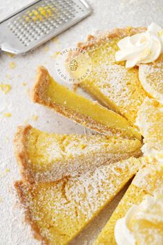 a lemon tart with powdered sugar on top and a grater in the background