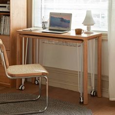 a laptop computer sitting on top of a wooden desk next to a lamp and chair