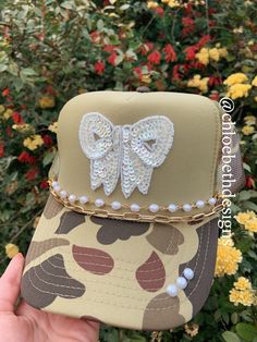 How stunning is this pearl bow hat!! Hat chains are removable and interchangeable with clasps on each side.  Please allow up to a week for this item to ship as it is a custom hat. Thank you!! For clarification when purchasing: If you purchase one of the hat chain options, this is individual hat chains and does not include the trucker hat. If you purchase the bling hat option, this option includes the trucker hat and all of the bling as pictured. Patch Hats Diy, Trucker Hat Diy, Camo Hats Outfits, Custom Hat Ideas, Print Shop Ideas, Camo Trucker Hat, Womens Camo, Camo Hats