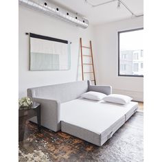 a couch with two pillows on top of it in front of a window and ladder