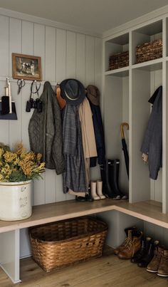 a coat rack with hats, boots and umbrellas hanging on the wall above it