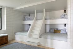 a room with bunk beds and stairs leading to the upper floor, along with a window