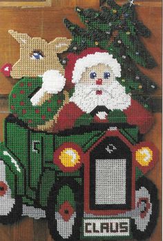 a cross stitch christmas ornament with santa driving a truck and reindeer on it