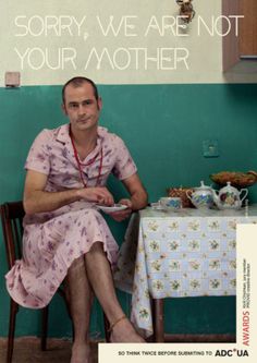 a man sitting at a table in front of a green wall with the words sorry, we are not your mother on it