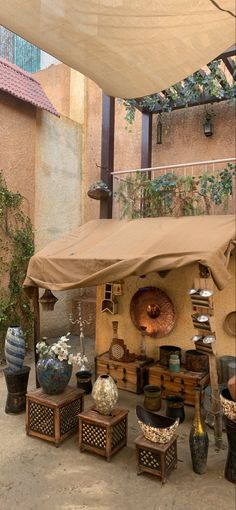 an outdoor area with pots, vases and tables under a large awning over it