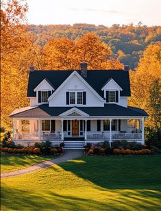 a large white house sitting in the middle of a lush green field next to trees