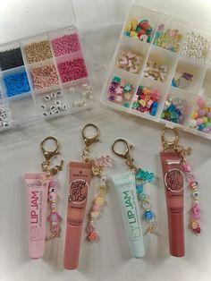 four different types of beads and charms in plastic containers with key chains attached to them