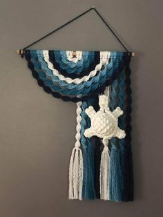 a blue and white wall hanging with two tassels on the end of it