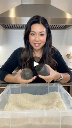 a woman holding an object in her hands while standing in front of a counter top