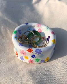 two rings are sitting in a flowered bowl on a white tablecloth covered surface