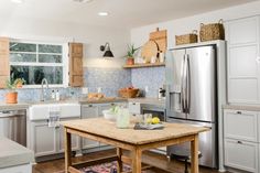 a kitchen with white cabinets and stainless steel appliances, including an island in the middle