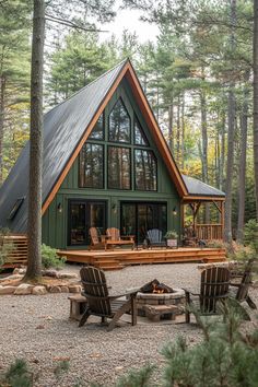 a large cabin in the woods with two chairs and a fire pit on the ground