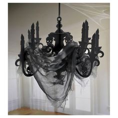 a black chandelier hanging from a ceiling in a room with white walls and curtains