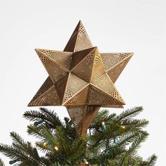 a star ornament hanging from the top of a christmas tree in front of a white background