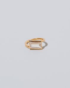 a gold ring with a baguette cut stone in the middle, on a white background