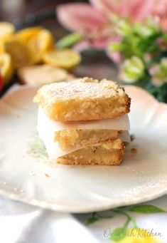 three pieces of cake sitting on top of a white plate next to flowers and lemons