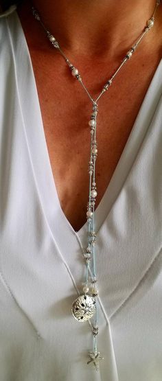 "Always bring a reminder of the ocean with you. This silk, hand knotted lariat has two beautiful focal pieces, a starfish and sand dollar. Surrounding them are crystals and fresh water pearls. The lariat is created on light blue silk. Each lariat is created upon order. There may be slight variations in the beads. This lariat does not have a clasp. Simply criss cross and flip one end over to make a Y and complete the necklace. Once worn, lariats look beautiful and do not tangle. You can accomplis Bohemian Lariat Necklace With Sliding Knot, Handmade Adjustable Lariat Necklace, Bohemian Lariat Necklace As Gift, Elegant Lariat Necklaces Hand Knotted, Adjustable Lariat Long Necklace For Festival, Elegant Hand-knotted Lariat Necklaces, Adjustable Multi-strand Lariat Necklace For Party, Elegant Lariat Necklace For Festivals, Elegant Long Lariat Necklace For Festivals