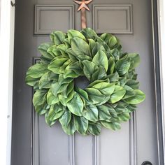 a wreath on the front door of a house with a star hanging from it's center