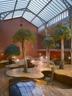 the inside of a building with tables and trees in it's centerpieces