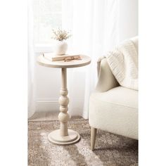 a white table sitting next to a chair in front of a window on top of a rug