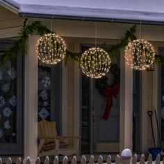 christmas lights hanging from the side of a house in front of a porch with snow on the ground