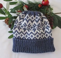 a blue and white knitted hat sitting on top of a table next to flowers