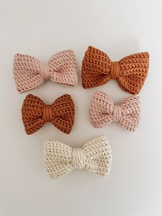 four crocheted bow ties laid out on a white surface