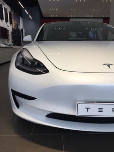 the front end of a white tesla car in a showroom at an automobile dealership