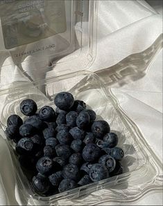 a plastic container filled with blueberries on top of a white cloth