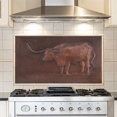 a cow is painted on the wall above an oven