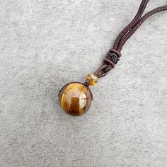 Discover the beauty, symbolism, and versatility of the Stone Sphere Rope Necklace as it becomes a unique expression of your style and connection to the energy of natural gemstones. Spheres are symbolic of completeness, unity, and the cyclical nature of life. The stone sphere on this necklace serves as a reminder of the interconnectedness of all things and the continuous flow of energy. The rope necklace is suitable for both everyday wear and special occasions. Its adjustable design and natural e Spiritual Round Agate Crystal Necklace, Spiritual Agate Crystal Necklace, Brown Amulet Necklace With Round Pendant, Brown Amulet Style Necklace With Round Pendant, Brown Amulet Style Round Pendant Necklace, Spiritual Agate Round Pendant Crystal Necklace, Spiritual Agate Crystal Necklace With Round Pendant, Brown Round Jewelry For Healing, Black Round Pendant Necklace Nature-inspired