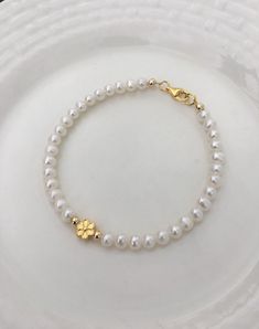 This elegant freshwater pearl bracelet features a beautiful flower charm, The charm and clasp are made of 925 Sterling Silver or 18K gold plated  Sterling Silver. If you need an extender chain, you can leave a note in the order. Elegant Gold Beaded Bracelet With Flower Charm, Gold Pearl Flower Bracelets, Elegant Beaded Bracelets With Flower Charm, Elegant Beaded Bracelets With Flower Charm And Round Beads, Dainty Gold Flower Pearl Bracelet, Flower Charm Bracelet, White Bracelet, Bangles Jewelry Designs, White Bracelets