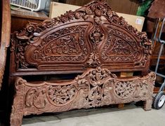 an ornate carved wooden bed frame with wheels