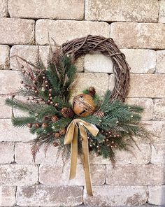 a wreath on a brick wall with pine cones and other greenery hanging from it